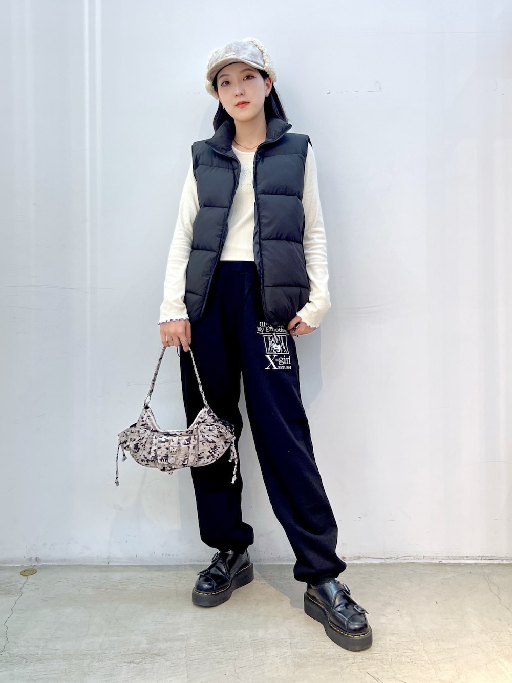 ブラック系のスウェットパンツ、ブラック系のダウンベスト、ホワイト系のTシャツ/カットソーを着用したレディースの秋コーディネートの1枚目の写真