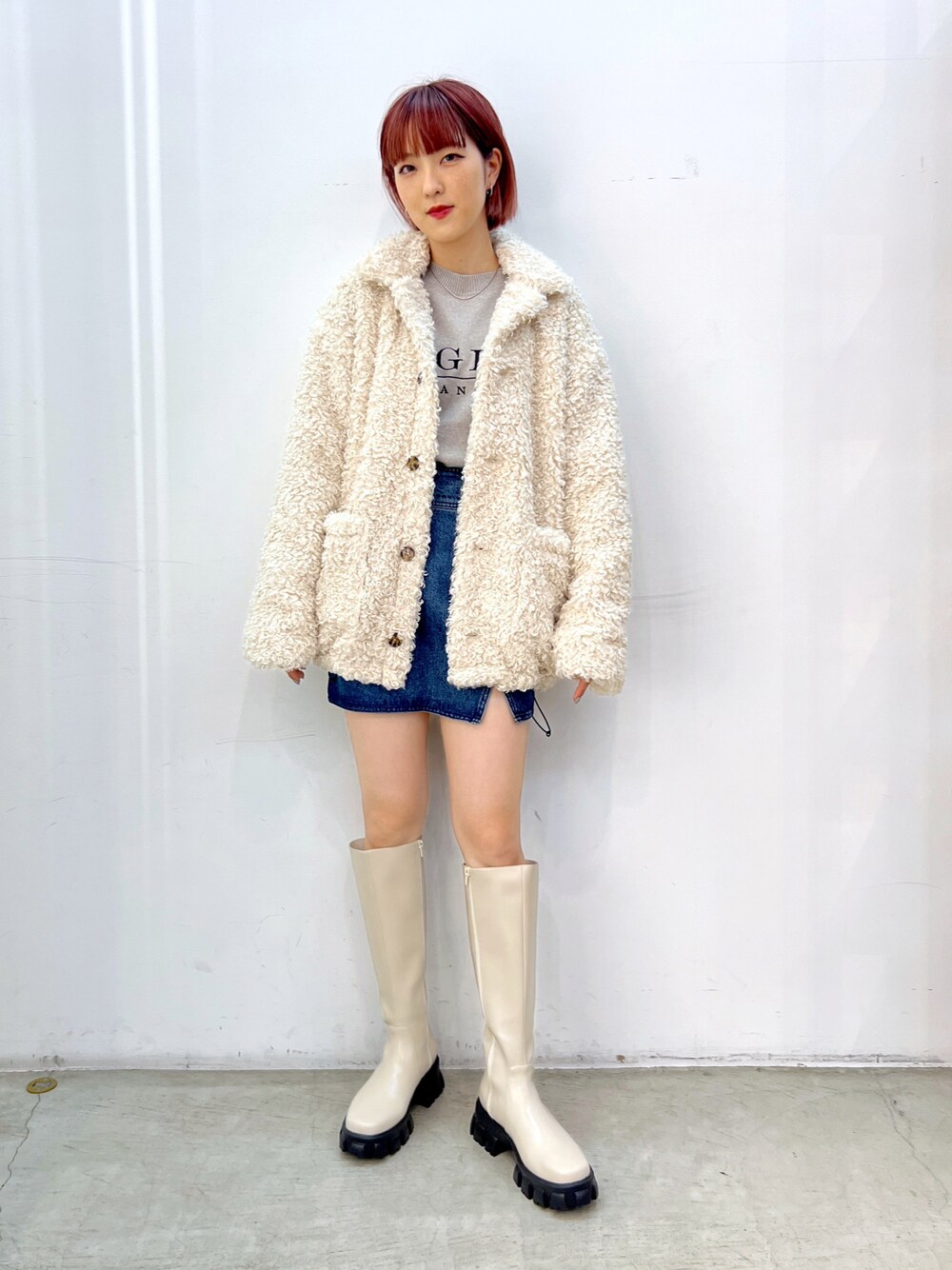 ホワイト系のブーツ、ブルー系のデニムスカート、グレー系のニット/セーターを着用したレディースの秋コーディネートの1枚目の写真