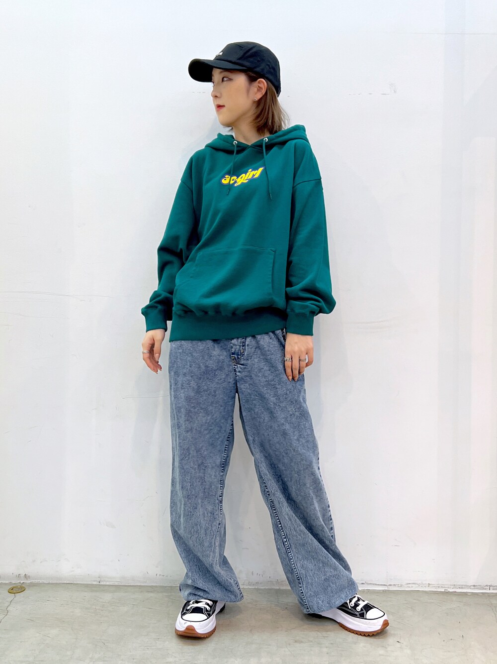 ブルー系のデニムパンツ、グリーン系のパーカー、ブラック系のキャップを着用したレディースの夏コーディネートの1枚目の写真