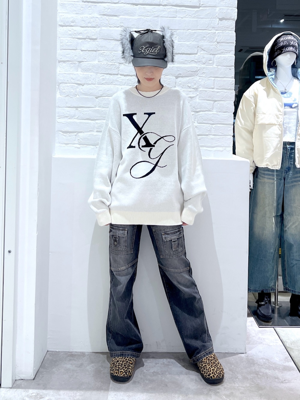 ブラック系のデニムパンツ、ホワイト系のニット/セーター、ブラック系のキャップを着用したレディースの秋コーディネートの1枚目の写真