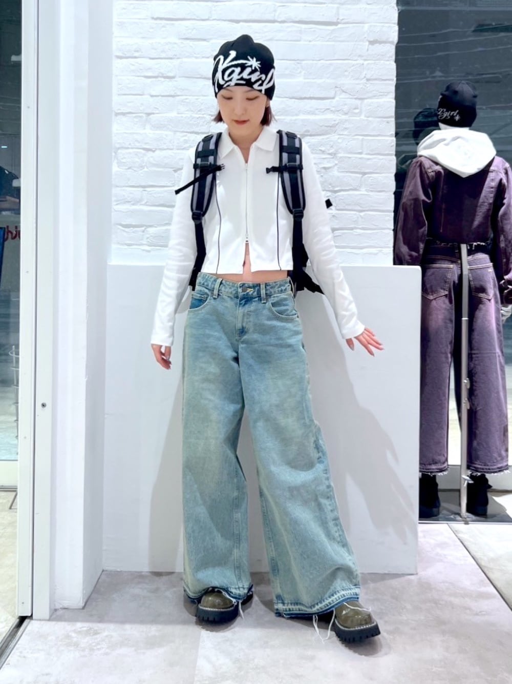 ブルー系のデニムパンツ、グレー系のバックパック/リュック、ホワイト系のTシャツ/カットソーを着用したレディースの冬コーディネートの1枚目の写真