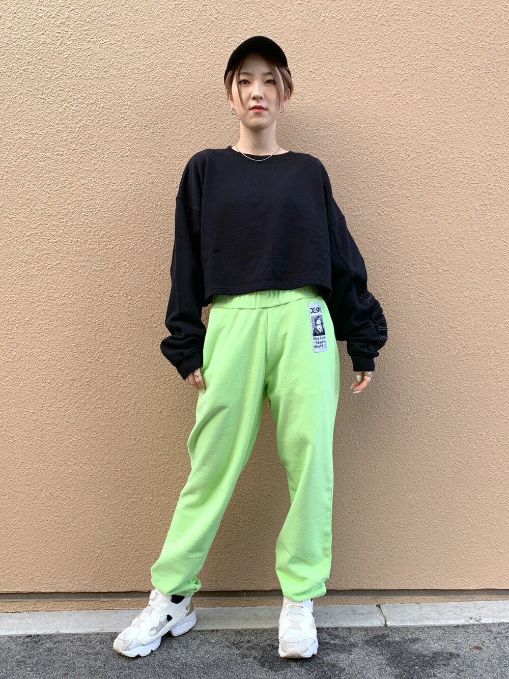 グリーン系のスウェットパンツ、ブラック系のスウェット、ブラック系のキャップを着用したレディースの冬コーディネートの1枚目の写真