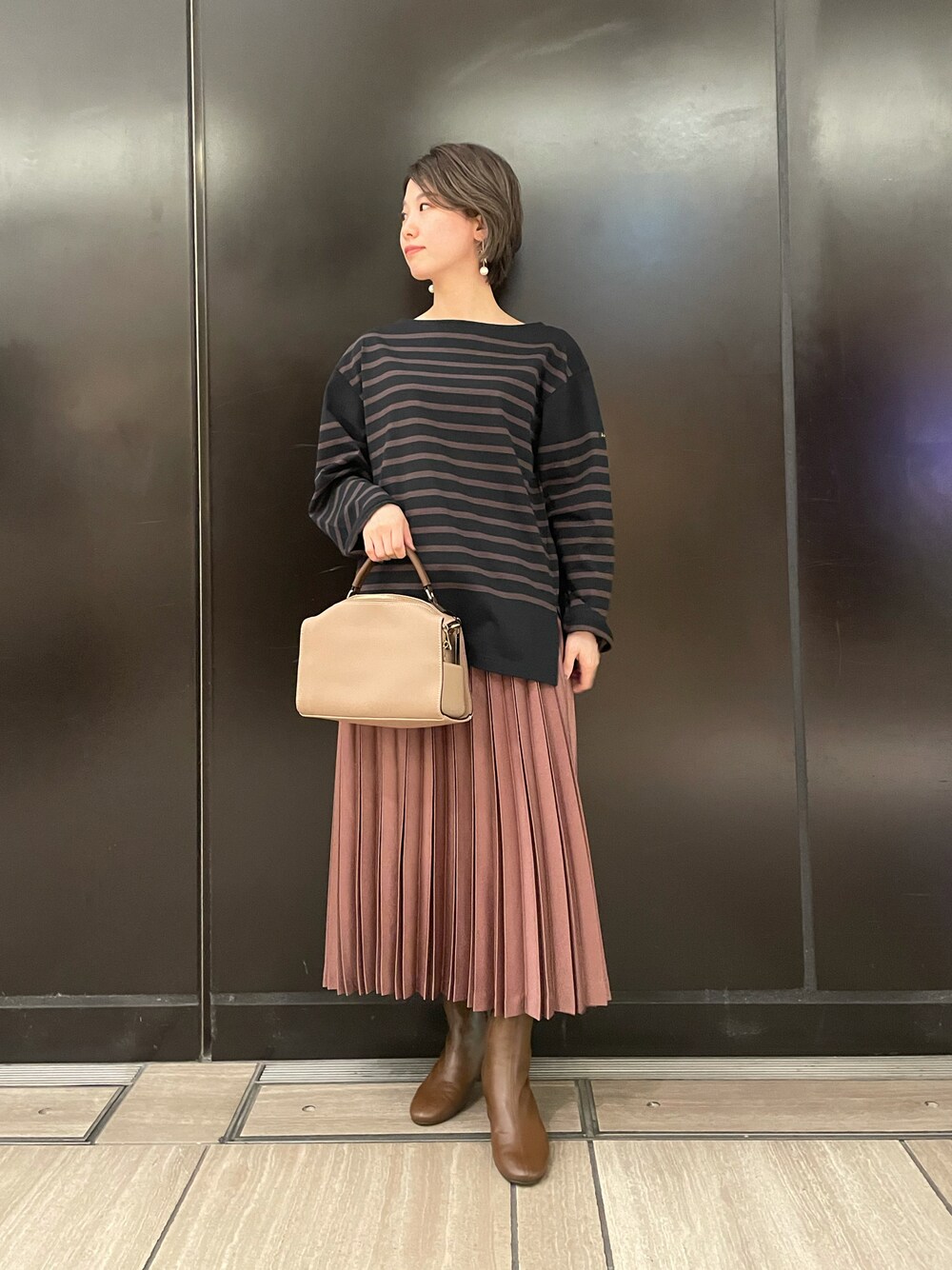 ブラウン系のTシャツ/カットソー、ベージュ系のボストンバッグ、ピンク系のスカートを着用したレディースの秋コーディネートの1枚目の写真