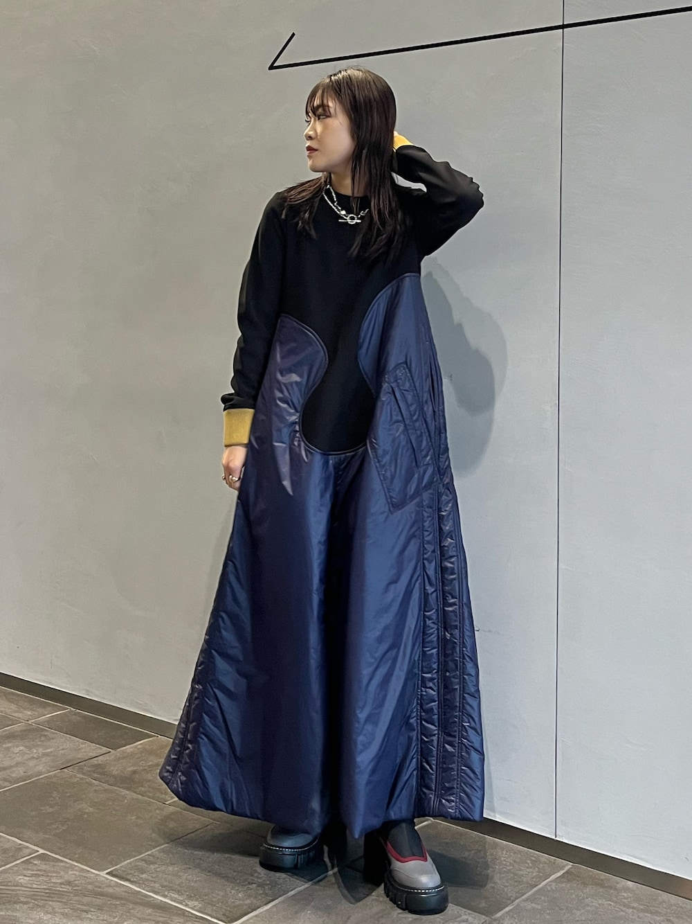 グレー系のブーツ、ブルー系のワンピース、シルバー系のネックレスを着用したレディースの秋コーディネートの1枚目の写真