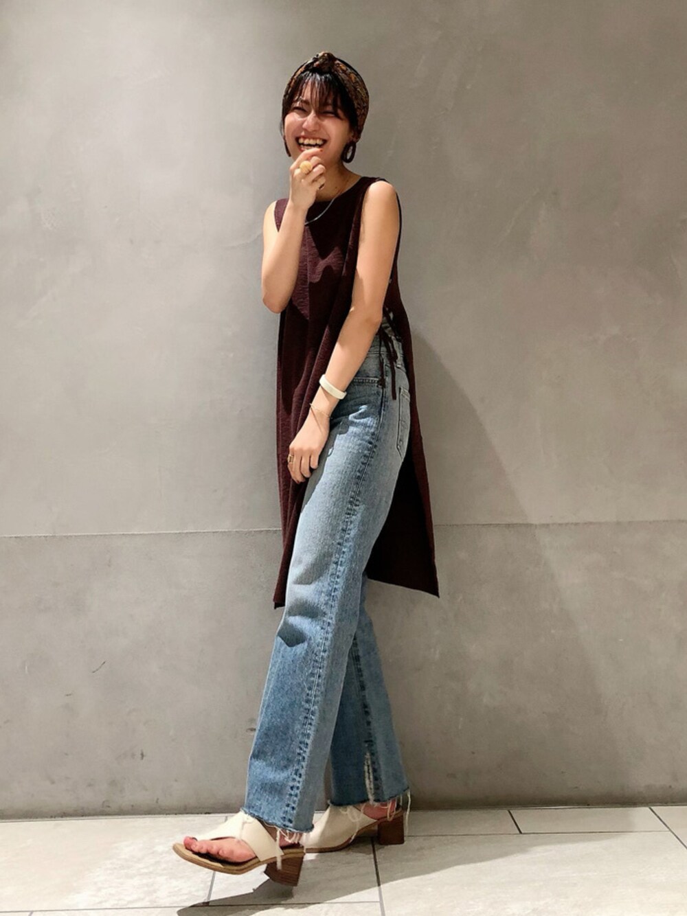 ブルー系のデニムパンツ、ブラウン系のベストを着用したレディースの春コーディネートの1枚目の写真