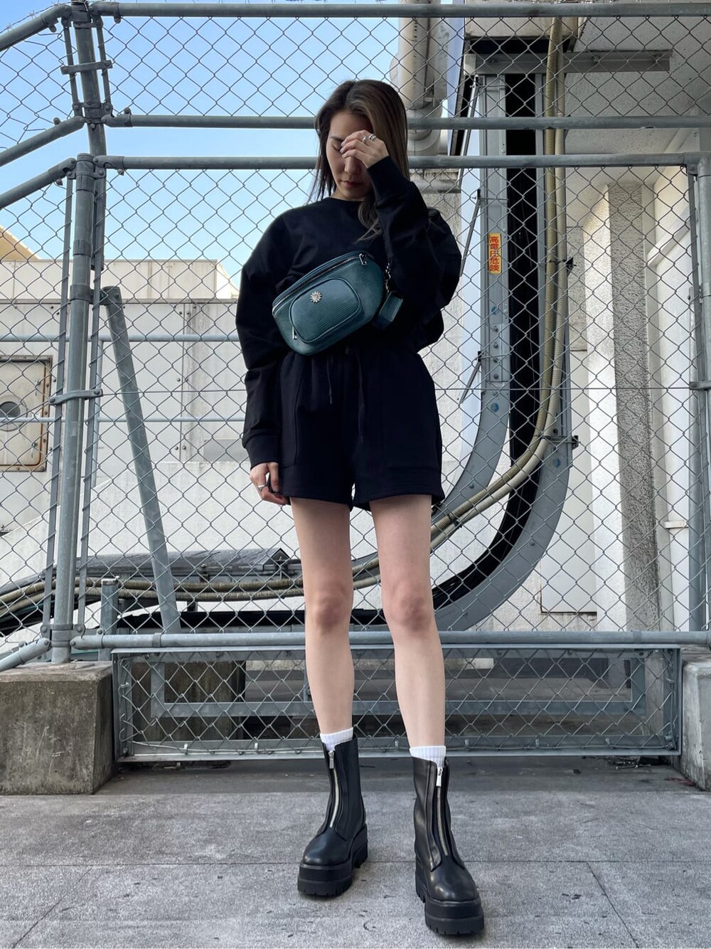 ブラック系のスウェットパンツ、ブラック系のブーツ、ブルー系のボディバッグ/ウエストポーチを着用したレディースの冬コーディネートの1枚目の写真