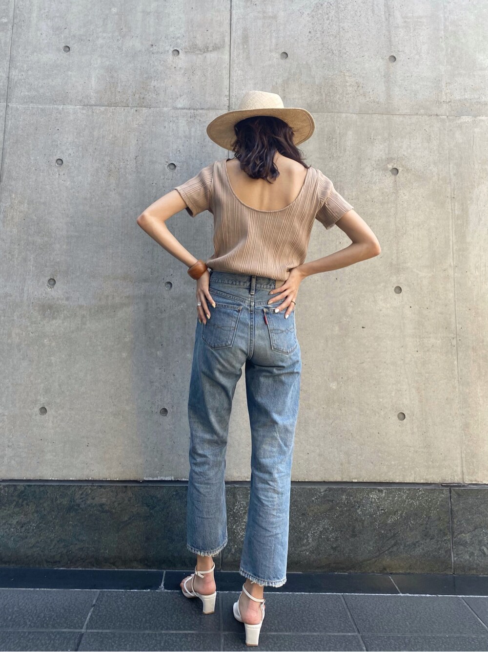 ブルー系のデニムパンツ、ベージュ系のTシャツ/カットソー、ベージュ系のハットを着用したレディースの春コーディネートの1枚目の写真