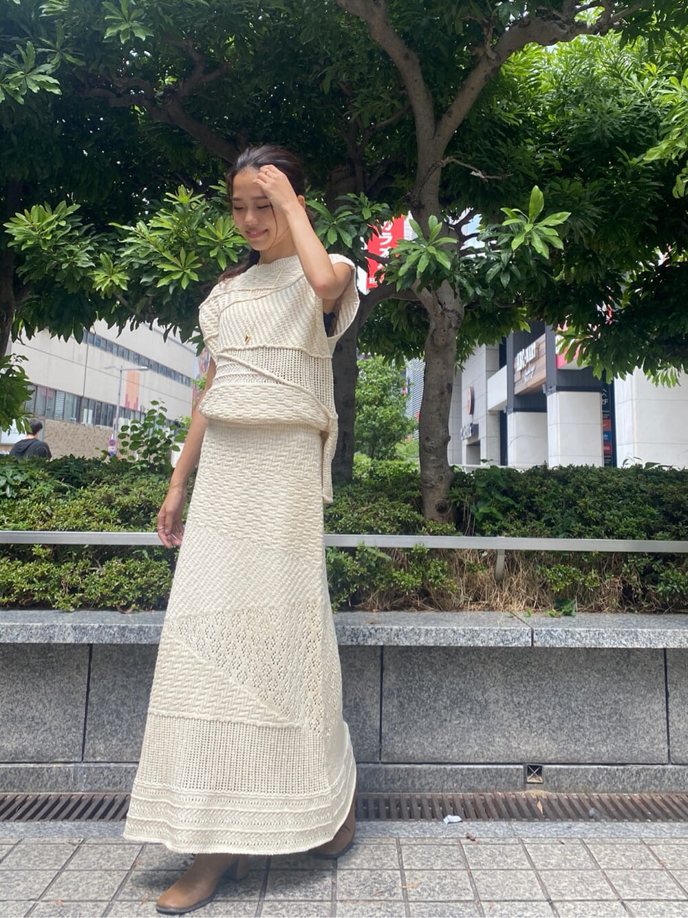 ホワイト系のスカート、ホワイト系のニット/セーター、ゴールド系のネックレスを着用したレディースの夏コーディネートの1枚目の写真