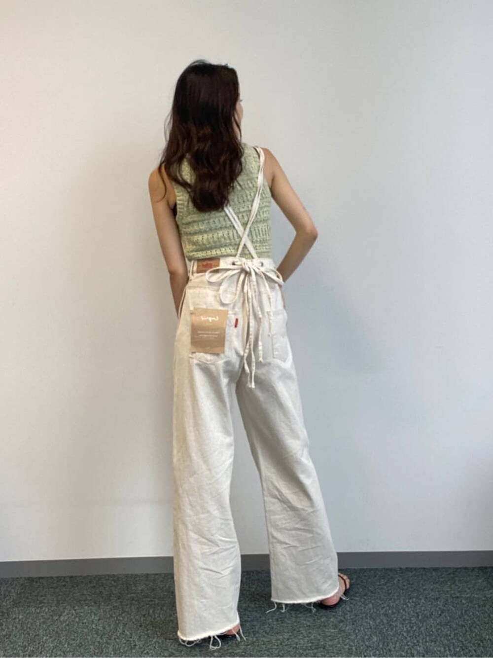 ホワイト系のデニムパンツ、グリーン系のニット/セーターを着用したレディースの春コーディネートの1枚目の写真