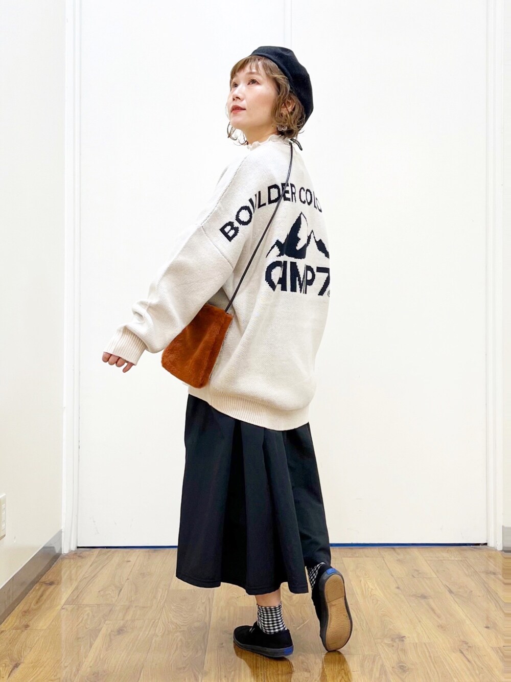 ホワイト系のニット/セーター、ホワイト系のTシャツ/カットソー、ブラック系のスカートを着用したレディースの秋コーディネートの1枚目の写真