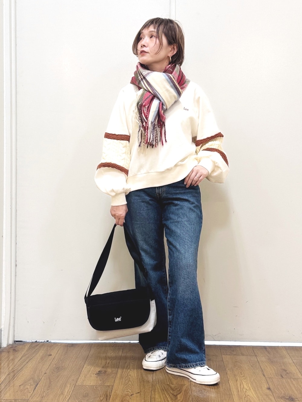 ブルー系のデニムパンツ、ホワイト系のスウェット、ブラック系のショルダーバッグを着用したレディースの冬コーディネートの1枚目の写真