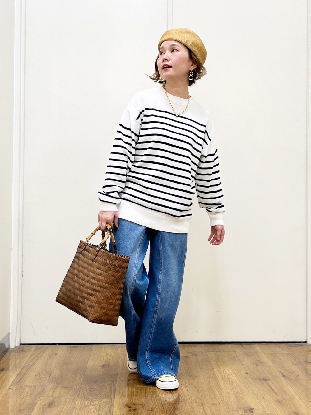 ブルー系のニット/セーター、ブルー系のデニムパンツ、ベージュ系のかごバッグを着用したレディースの春コーディネートの1枚目の写真