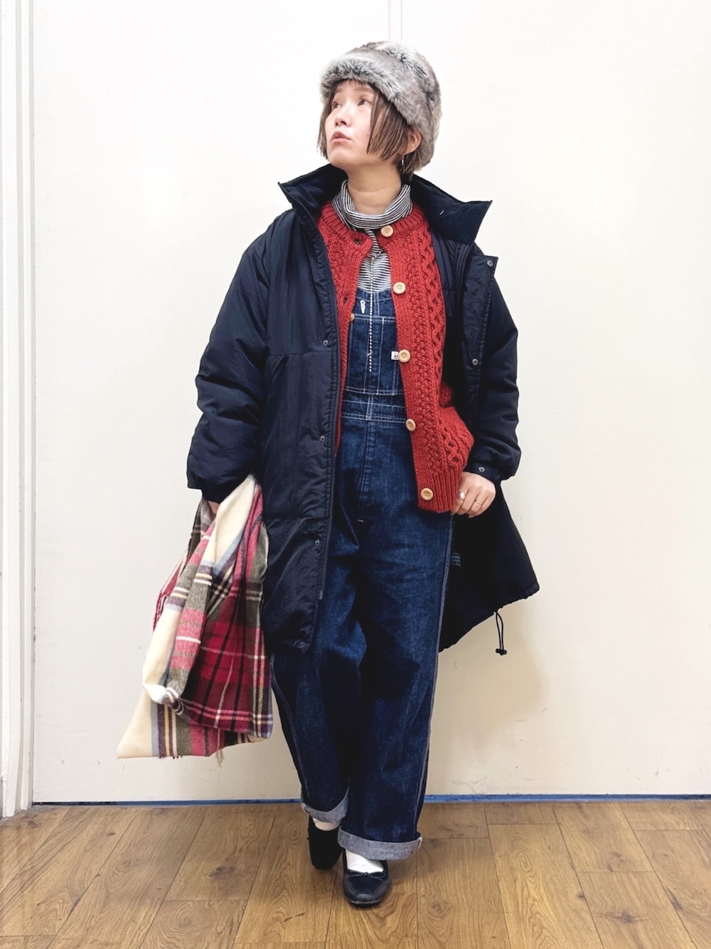 ブルー系のサロペット/オーバーオール、ブラック系のダウンジャケット/コート、レッド系のニット/セーターを着用したレディースの冬コーディネートの1枚目の写真