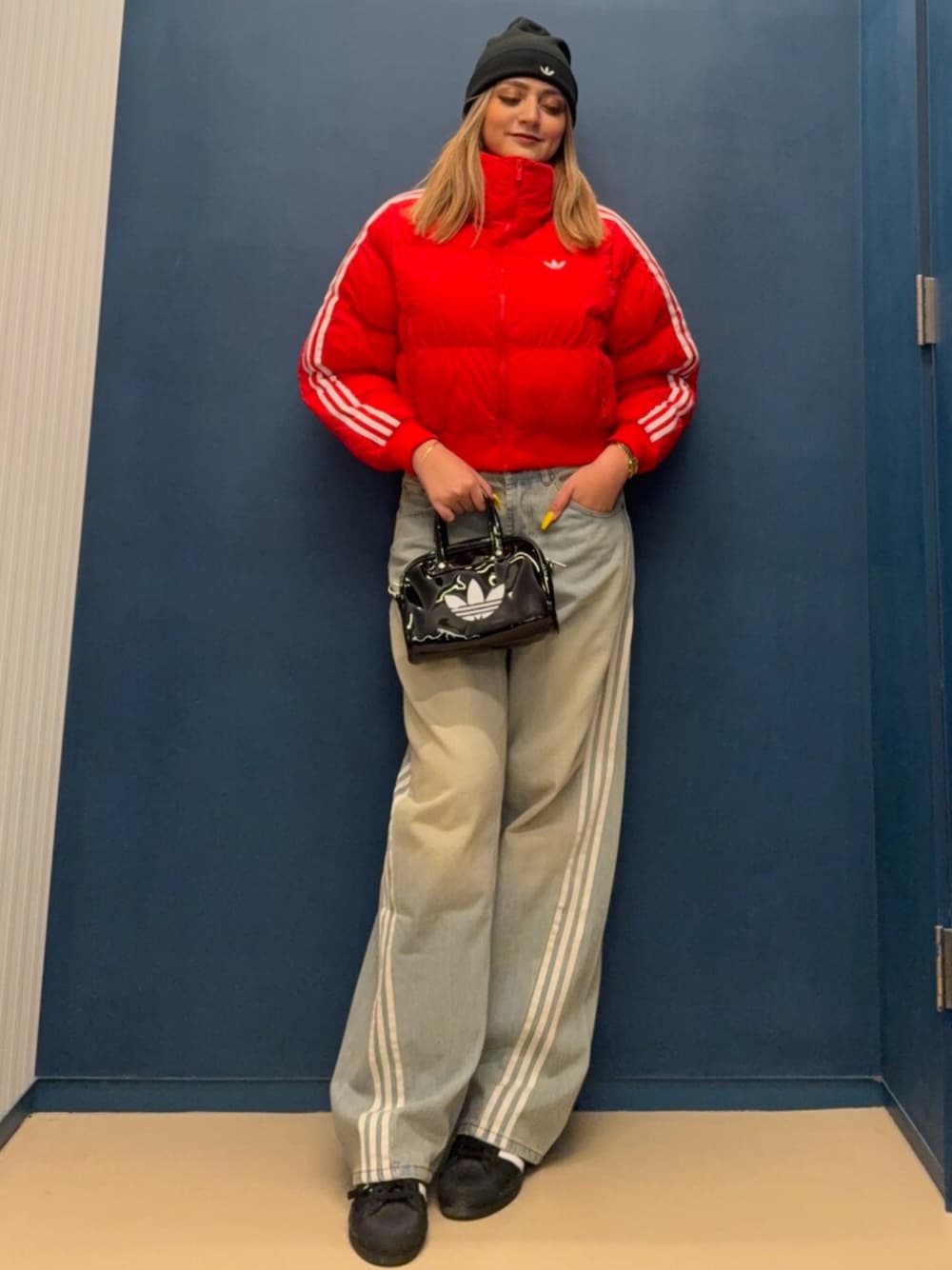 ブラック系のショルダーバッグ、レッド系のダウンジャケット/コート、ブルー系のデニムパンツを着用したレディースの秋コーディネートの1枚目の写真