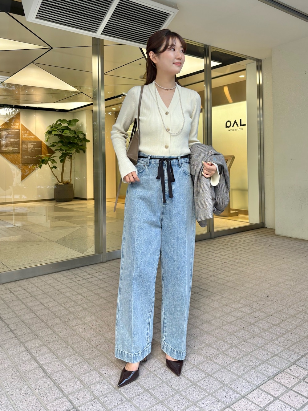 ブルー系のデニムパンツ、ブラウン系のパンプス、ブラウン系のショルダーバッグを着用したレディースの秋コーディネートの1枚目の写真