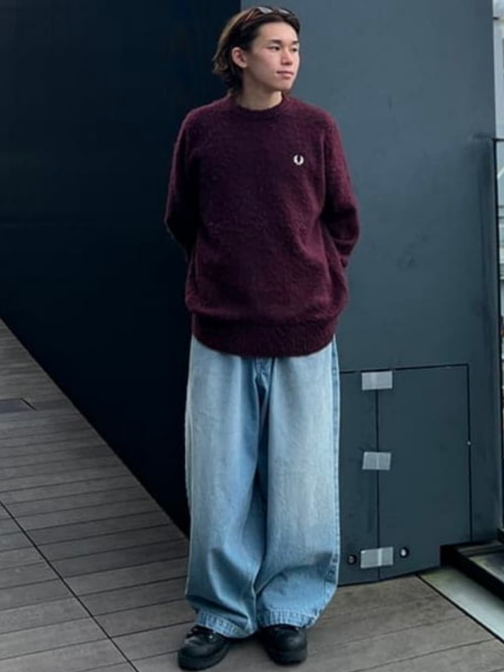 レッド系のニット/セーター、ブルー系のデニムパンツを着用したメンズの夏コーディネートの1枚目の写真