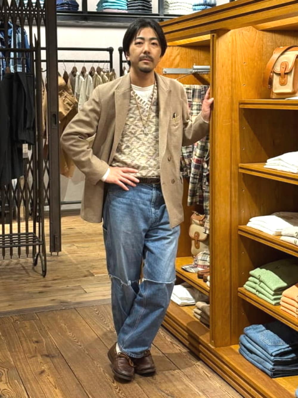 ブルー系のデニムパンツ、ベージュ系のニット/セーター、ホワイト系のTシャツ/カットソーを着用したメンズの春コーディネートの1枚目の写真