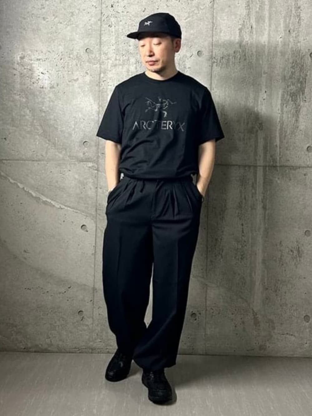 ブルー系のスラックス、ブラック系のTシャツ/カットソー、ブラック系のスニーカーを着用したメンズの春コーディネートの1枚目の写真