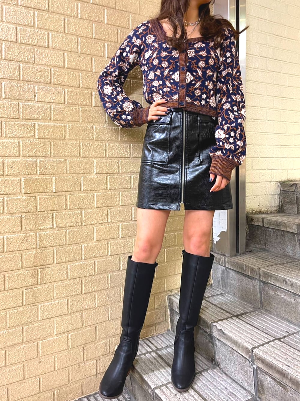 ブルー系のニット/セーター、ブラック系のスカート、ブラック系のブーツを着用したレディースの秋コーディネートの1枚目の写真