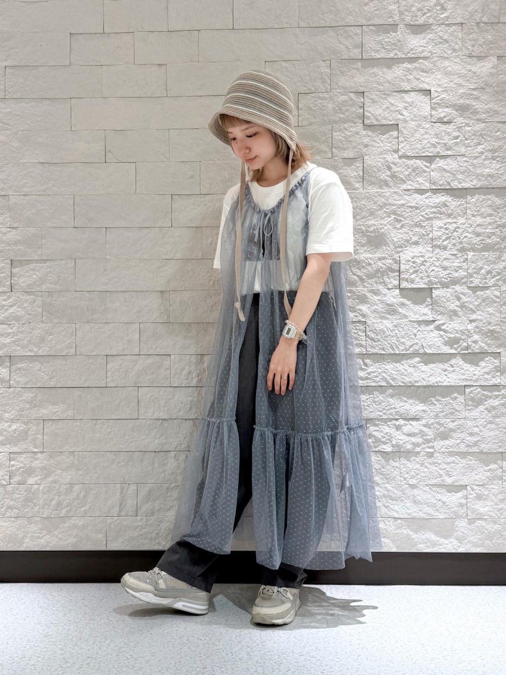 グレー系のパンツ、グレー系のスニーカー、ブラウン系のハットを着用したレディースの夏コーディネートの1枚目の写真