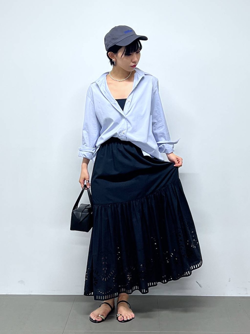 ブラック系のサンダル、ブラック系のハンドバッグ、ブルー系のシャツ/ブラウスを着用したレディースの夏コーディネートの1枚目の写真