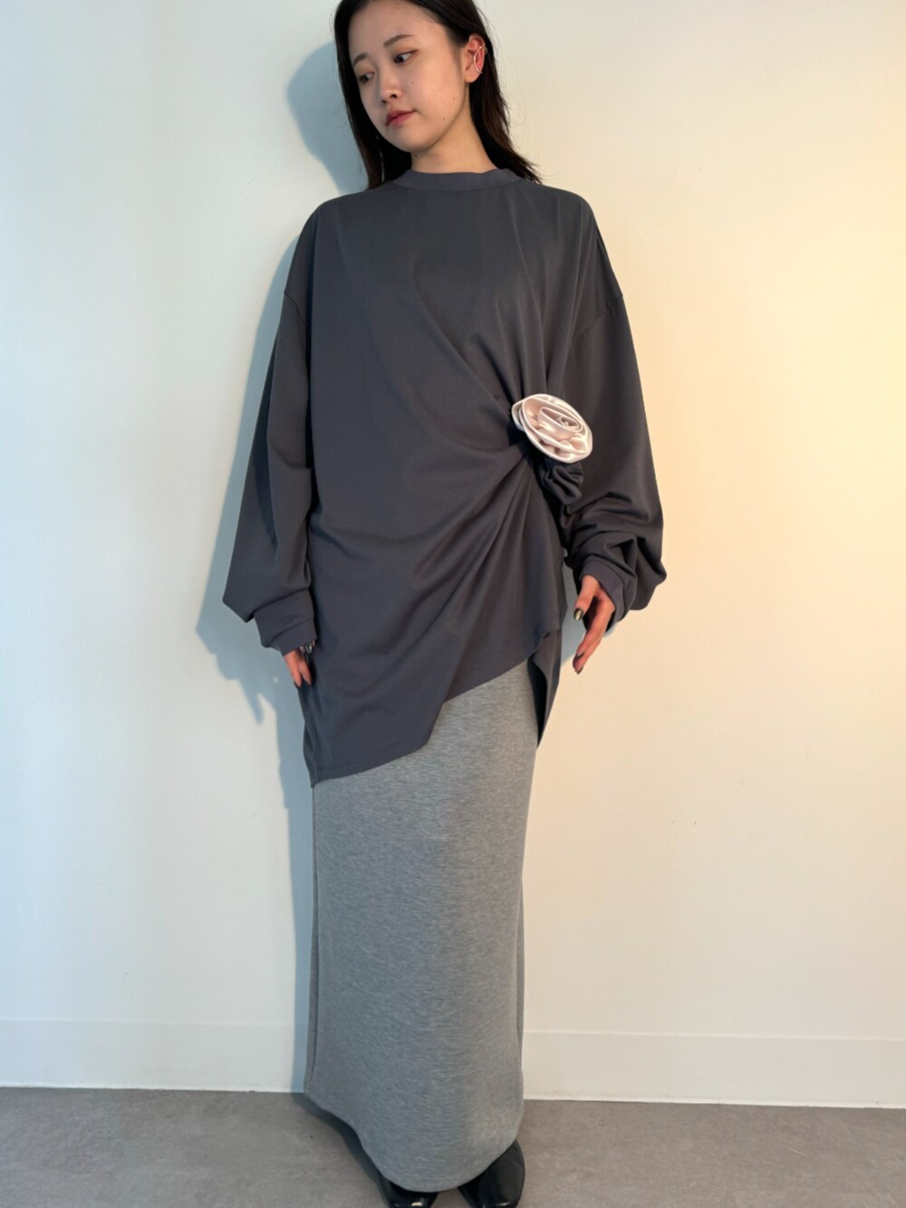 グレー系のTシャツ/カットソー、グレー系のスカート、シルバー系のイヤーカフを着用したレディースの秋コーディネートの1枚目の写真