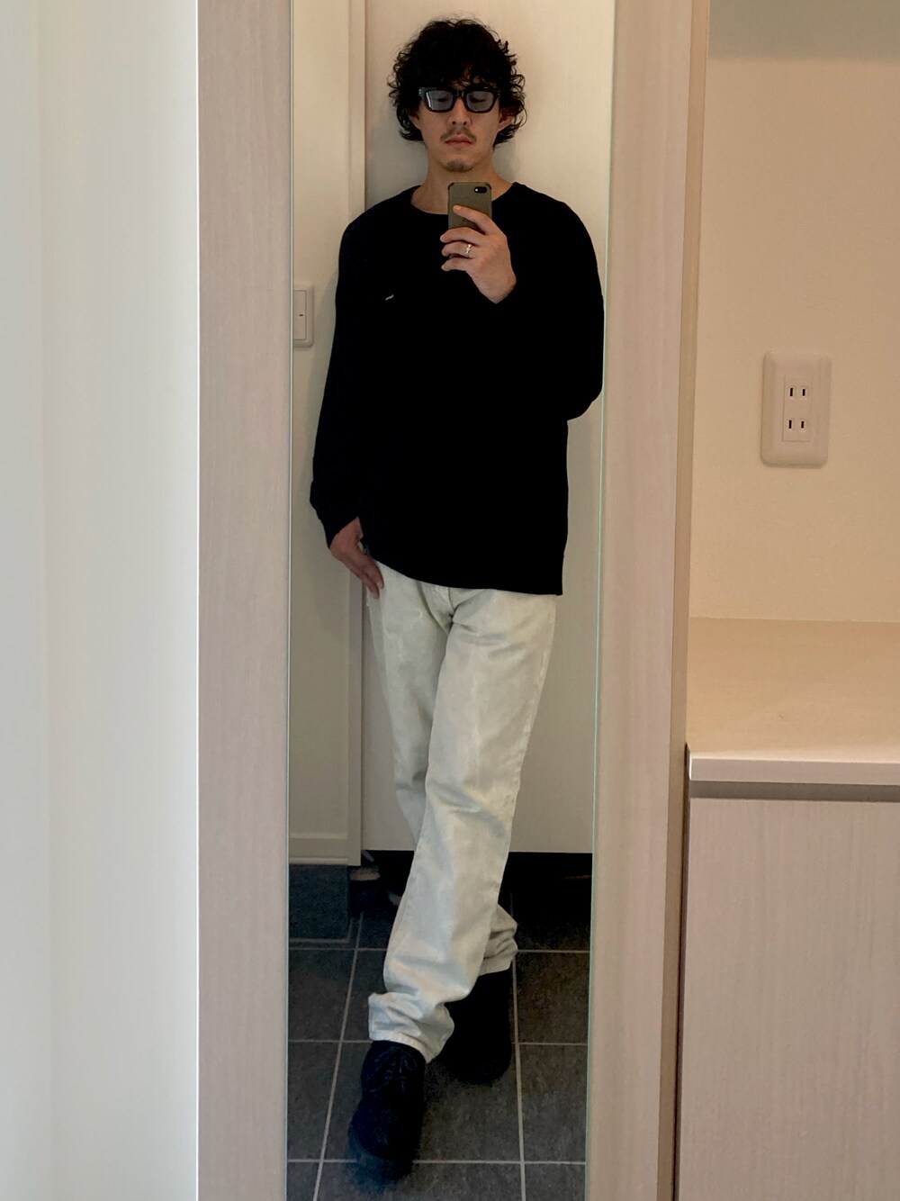ブラック系のニット/セーター、ホワイト系のデニムパンツ、ブラック系のドレスシューズを着用したメンズの秋コーディネートの1枚目の写真