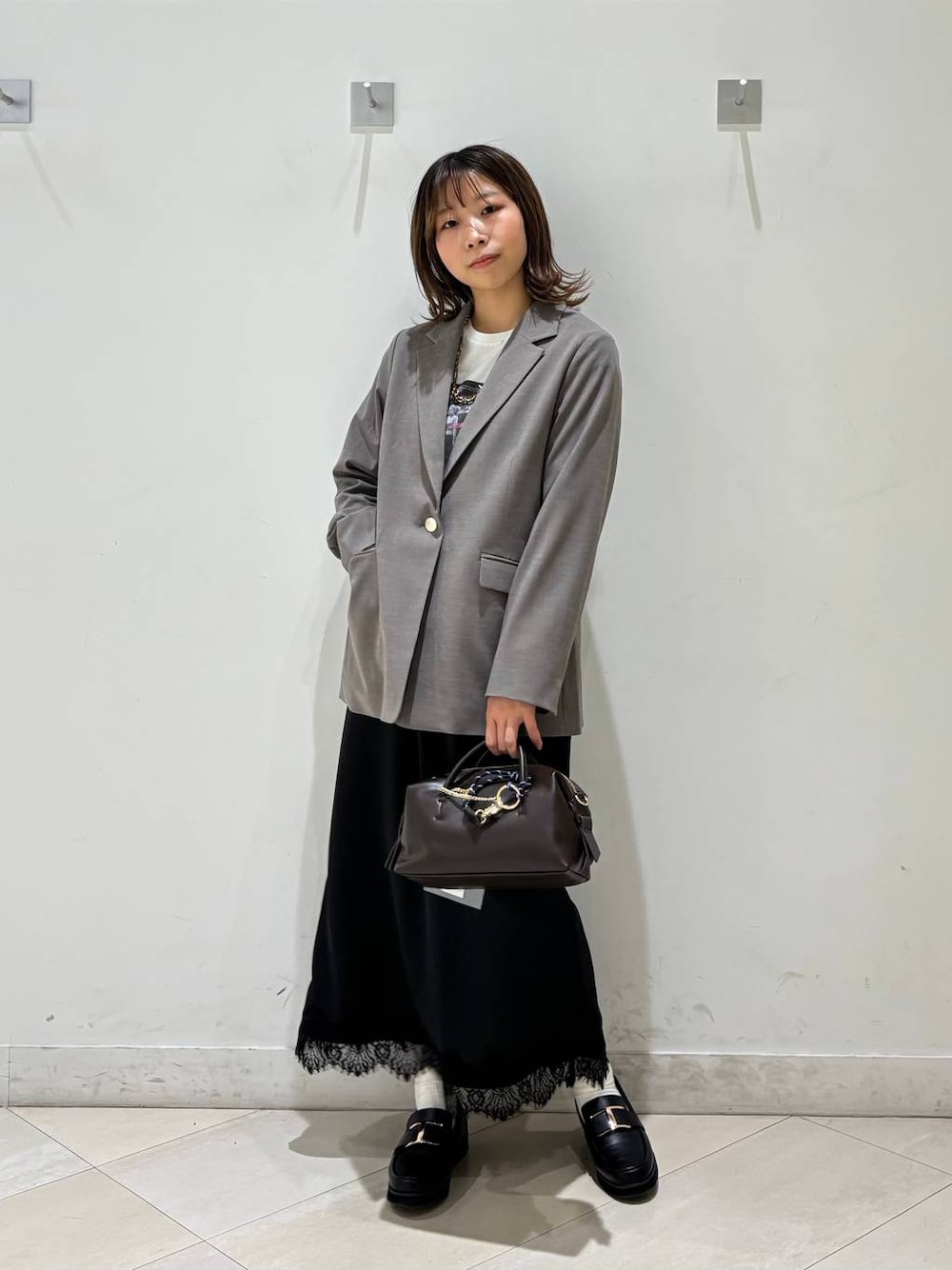 ブラック系のローファー、ブラウン系のテーラードジャケット、ブラウン系のボストンバッグを着用したレディースの春コーディネートの1枚目の写真