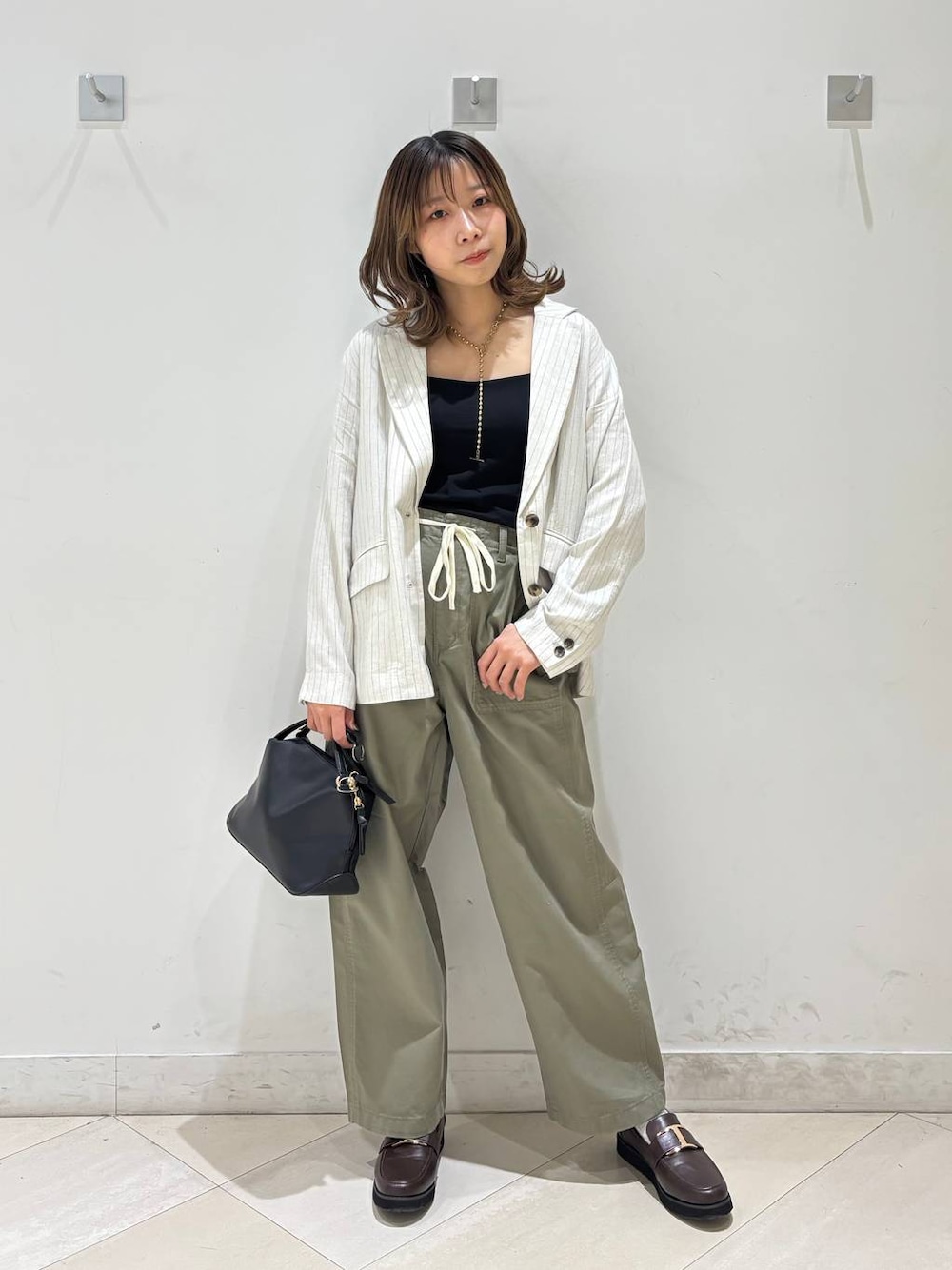 ブラック系のショルダーバッグ、ブラウン系のローファー、ブラック系のキャミソールを着用したレディースの春コーディネートの1枚目の写真