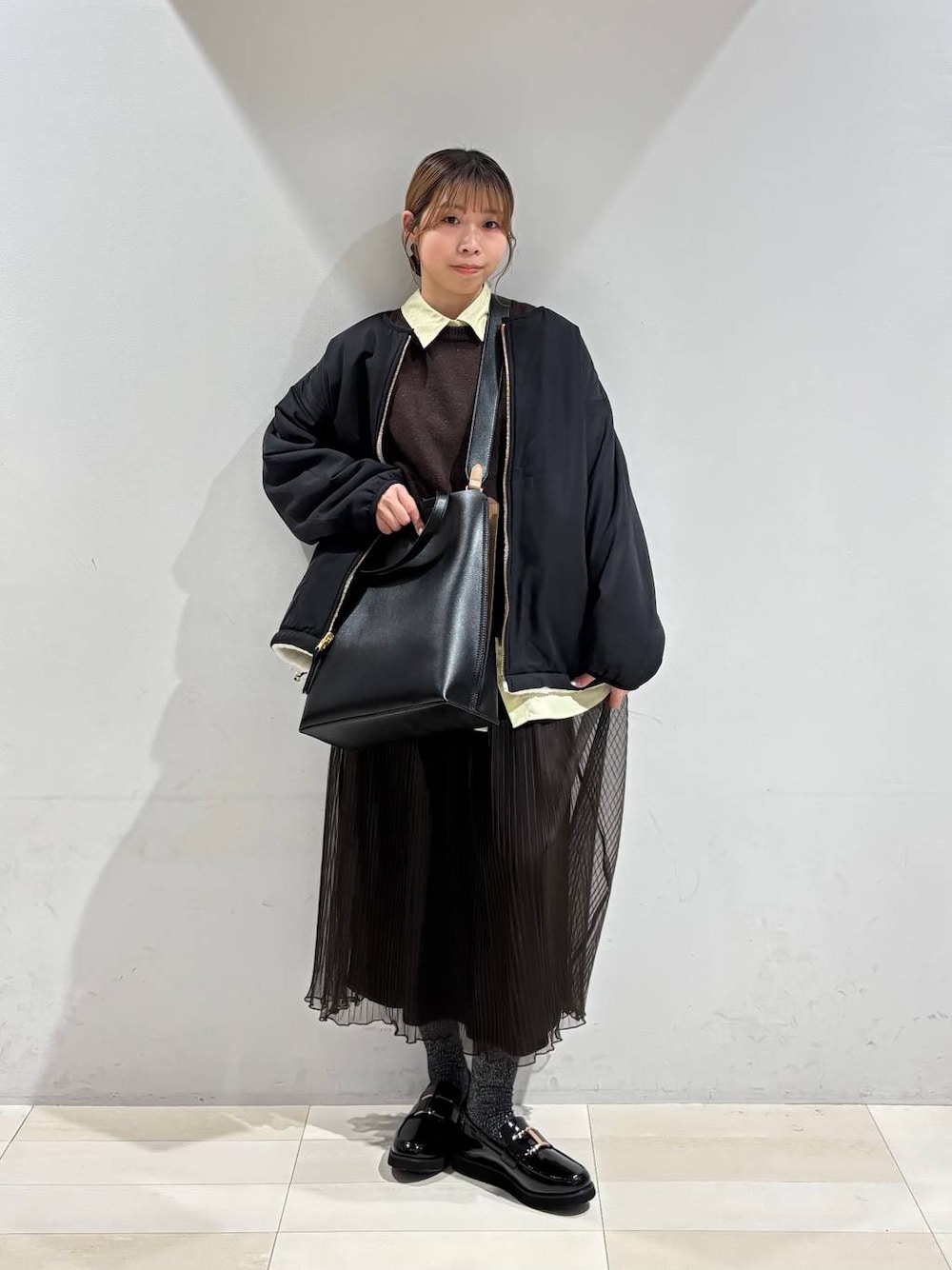 ブラック系のローファー、ブラック系のトートバッグ、ホワイト系のブルゾンを着用したレディースの秋コーディネートの1枚目の写真