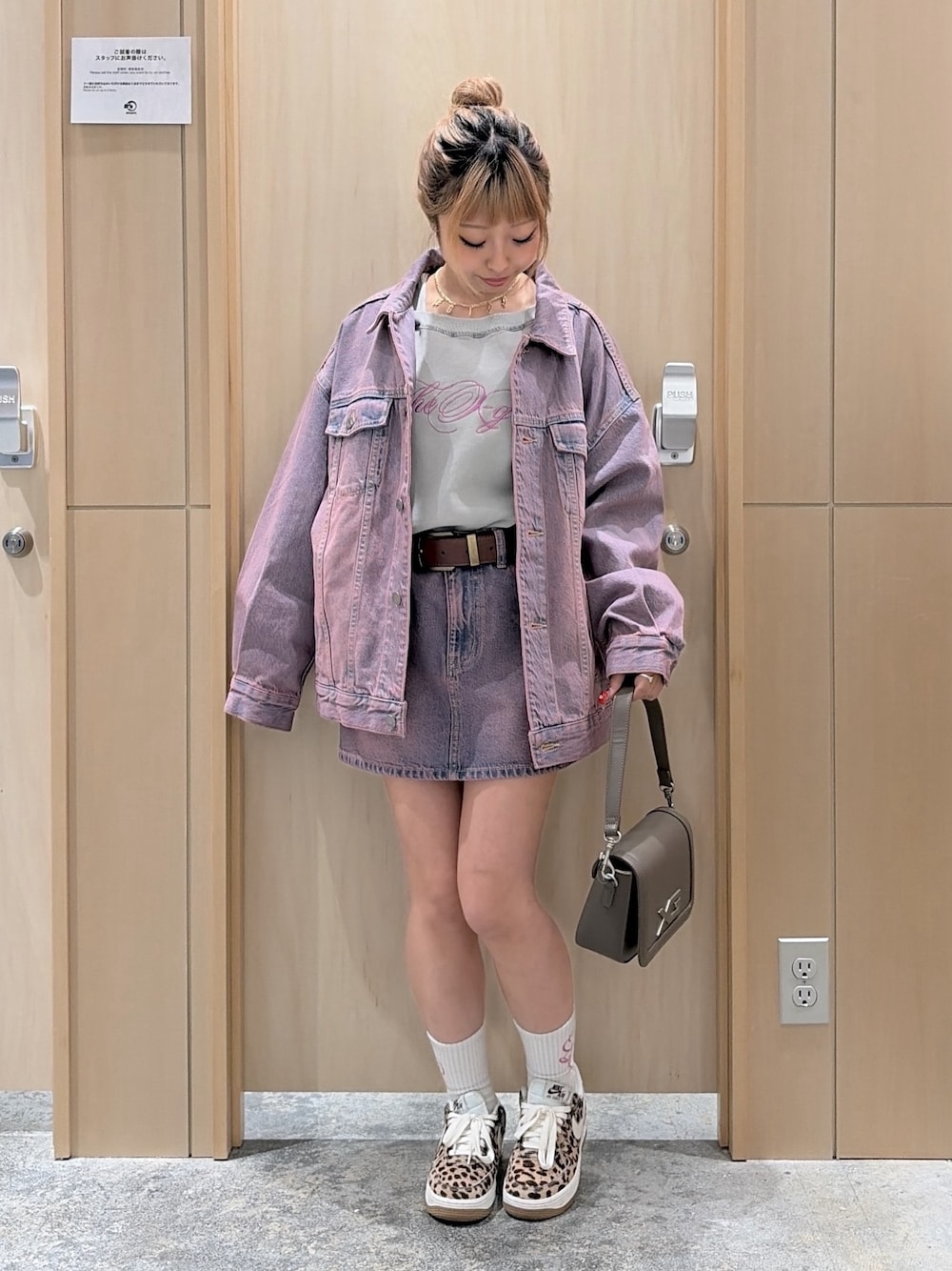 ピンク系のデニムジャケット、ピンク系のデニムスカート、ブラウン系のショルダーバッグを着用したレディースの冬コーディネートの1枚目の写真