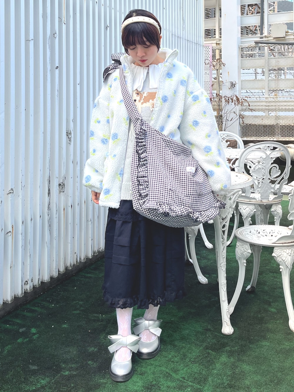 ブラック系のショルダーバッグ、ブルー系のニット/セーター、ホワイト系のシャツ/ブラウスを着用したレディースの冬コーディネートの1枚目の写真