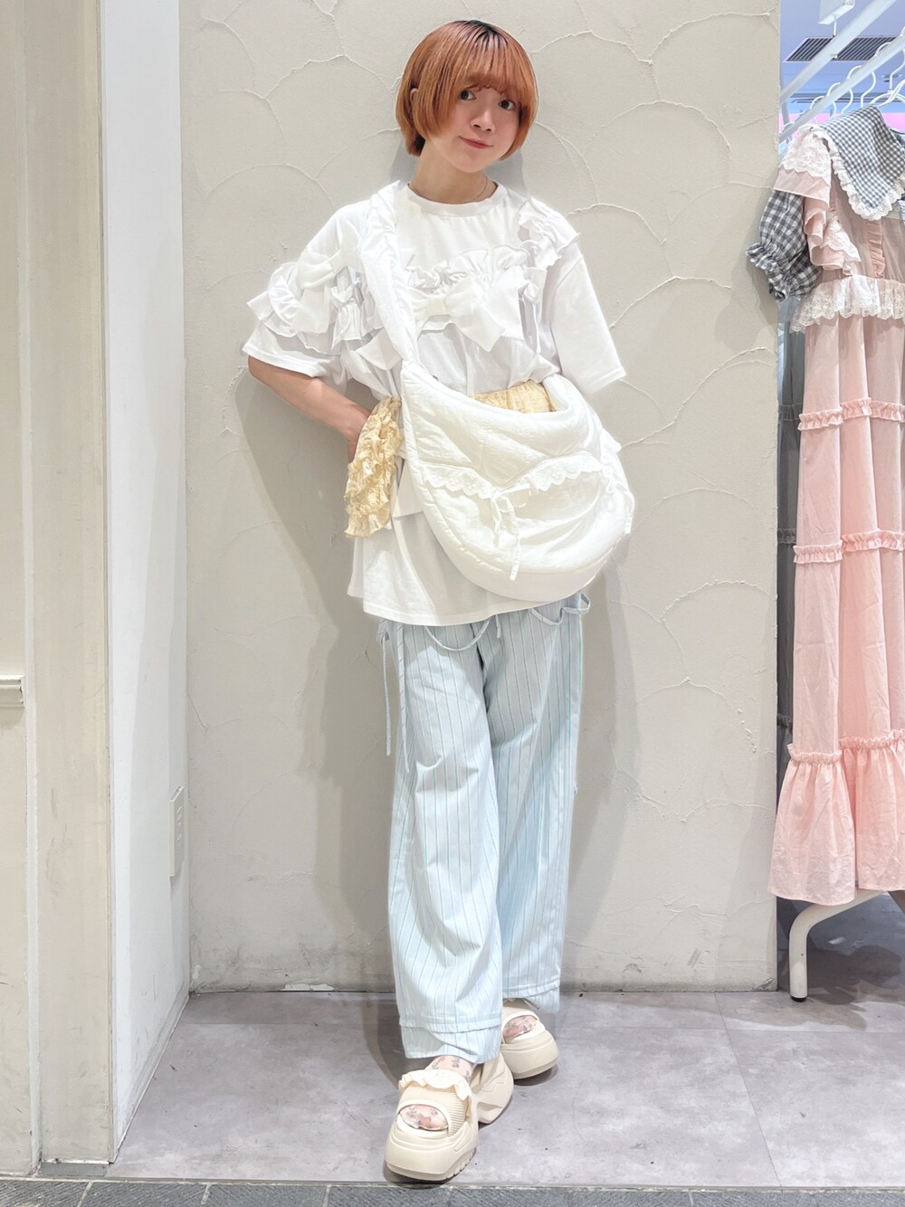 ホワイト系のショルダーバッグ、ホワイト系のTシャツ/カットソー、ブルー系のスラックスを着用したレディースの夏コーディネートの1枚目の写真