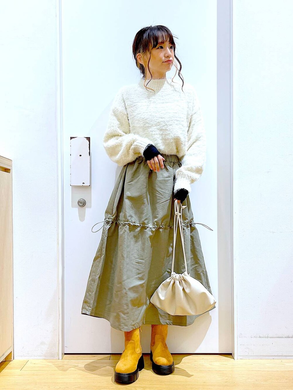 ベージュ系のショルダーバッグ、ベージュ系のブーツ、ベージュ系のニット/セーターを着用したレディースの冬コーディネートの1枚目の写真