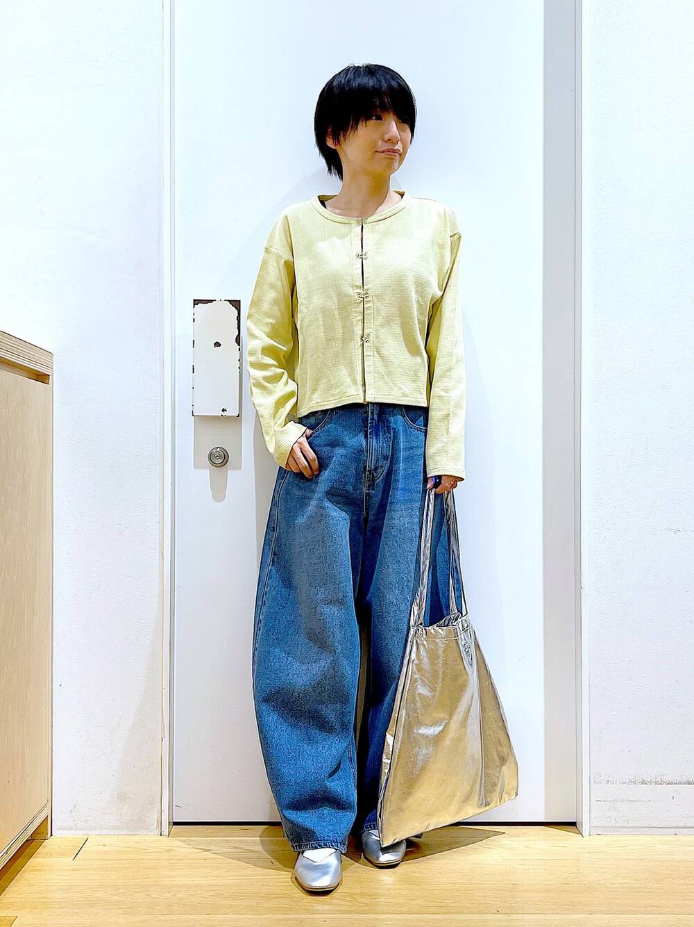 シルバー系のトートバッグ、ブルー系のデニムパンツ、シルバー系のパンプスを着用したレディースの春コーディネートの1枚目の写真