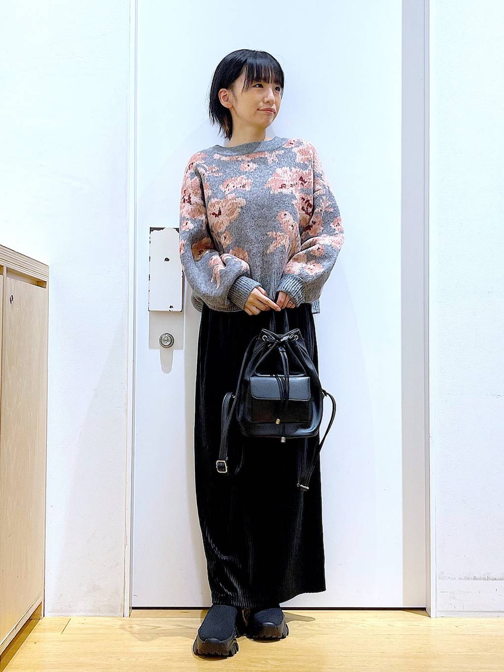 ブラック系のバックパック/リュック、ブラック系のスカート、ブラック系のブーツを着用したレディースの秋コーディネートの1枚目の写真