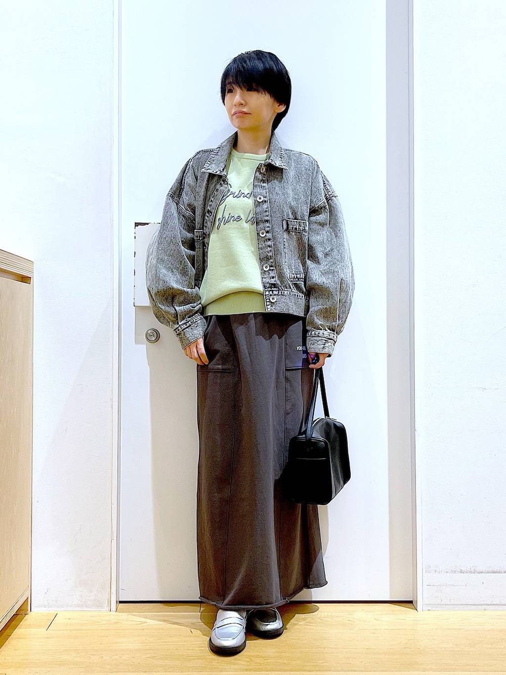 ブラック系のショルダーバッグ、シルバー系のローファー、ブラック系のデニムジャケットを着用したレディースの春コーディネートの1枚目の写真