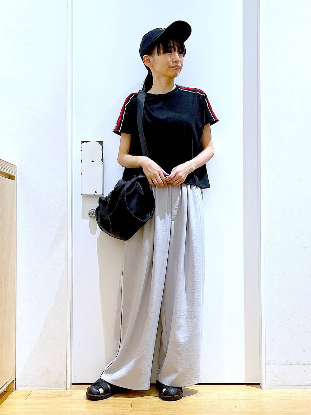 ブラック系のショルダーバッグ、ブラック系のスリッポン、ブラック系のTシャツ/カットソーを着用したレディースの春コーディネートの1枚目の写真