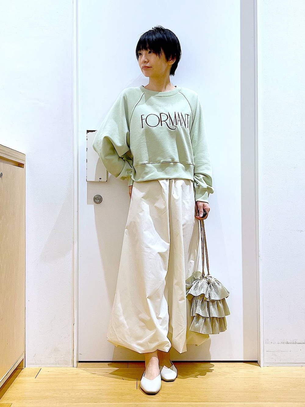 ホワイト系のパンプス、ベージュ系のショルダーバッグ、グリーン系のスウェットを着用したレディースの春コーディネートの1枚目の写真