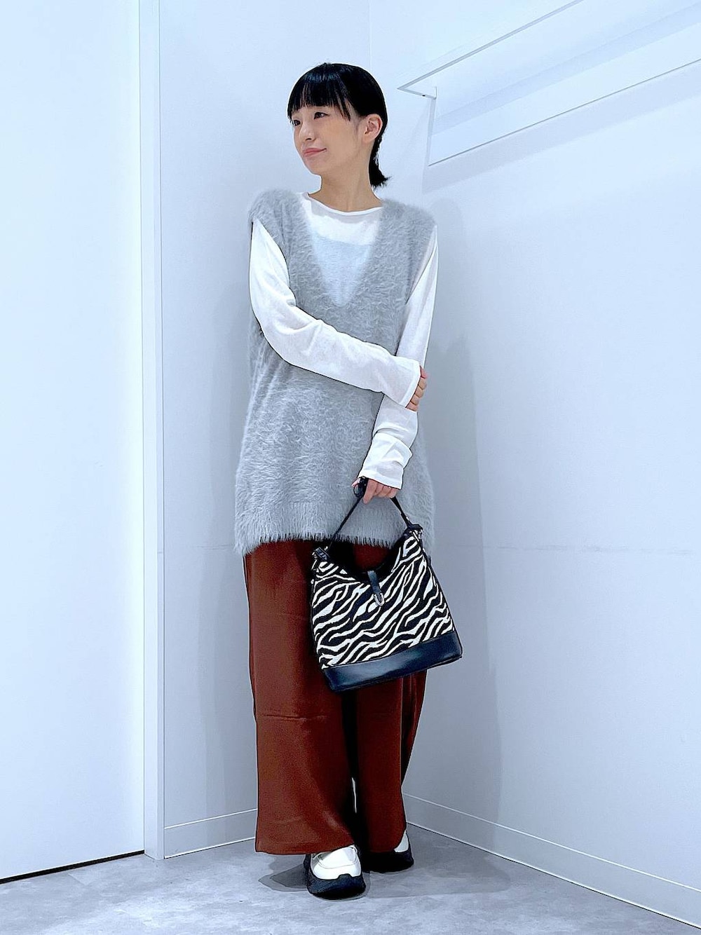 ホワイト系のTシャツ/カットソー、ホワイト系のローファー、グレー系のベストを着用したレディースの秋コーディネートの1枚目の写真