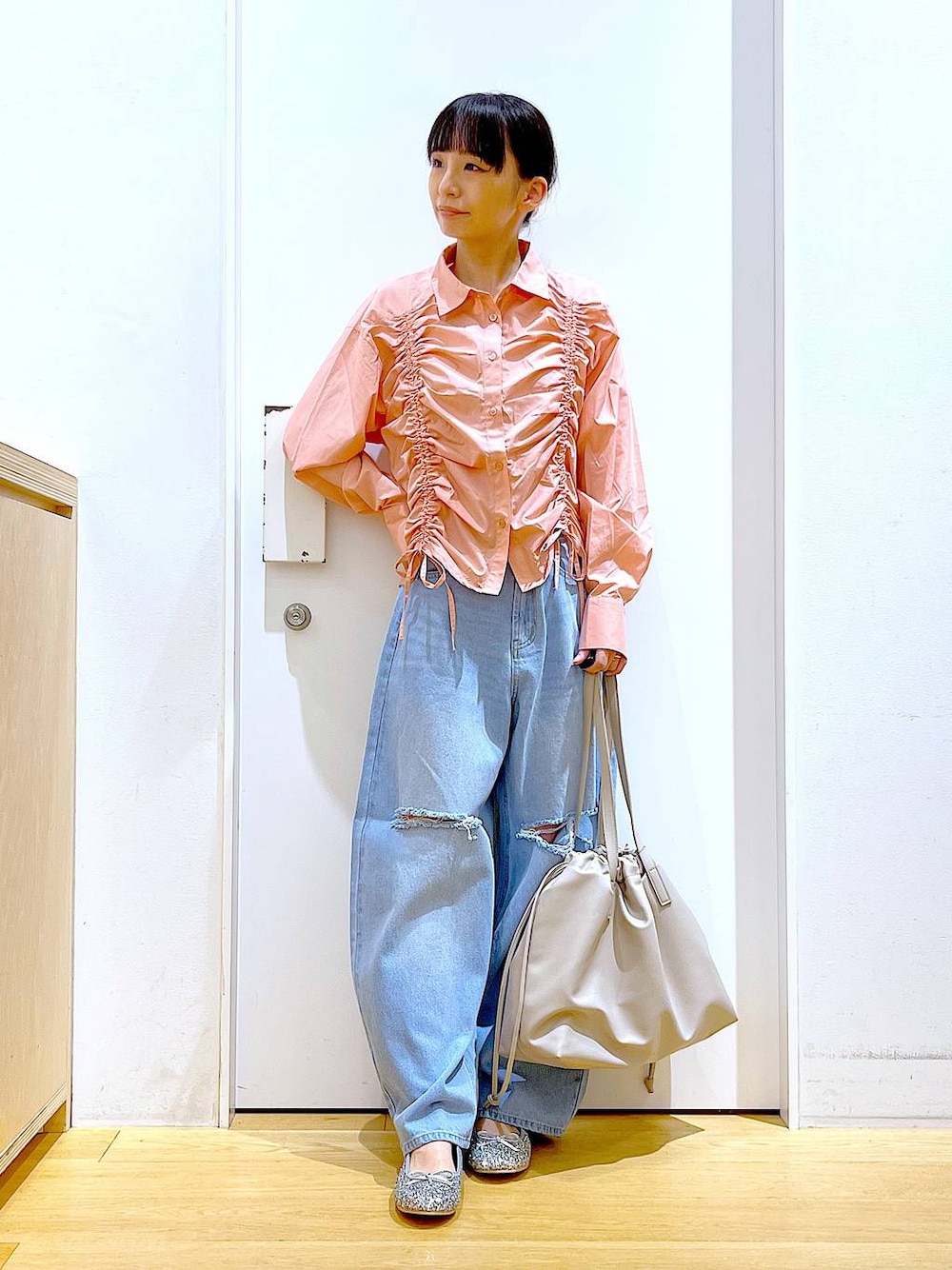 ベージュ系のトートバッグ、ブルー系のデニムパンツ、シルバー系のパンプスを着用したレディースの秋コーディネートの1枚目の写真