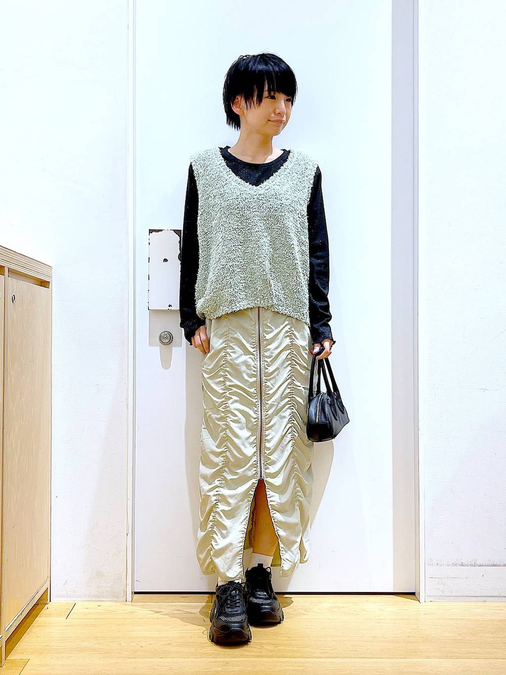 ベージュ系のスカート、ブラック系のボストンバッグ、ブラック系のTシャツ/カットソーを着用したレディースの春コーディネートの1枚目の写真