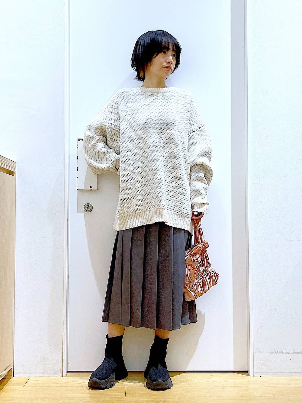 ベージュ系のニット/セーター、ピンク系のショルダーバッグ、ブラック系のブーツを着用したレディースの冬コーディネートの1枚目の写真