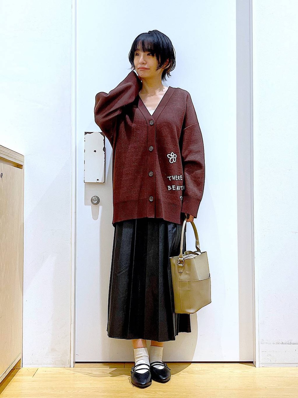 ブラック系のパンプス、ブラック系のスカート、ベージュ系のショルダーバッグを着用したレディースの秋コーディネートの1枚目の写真