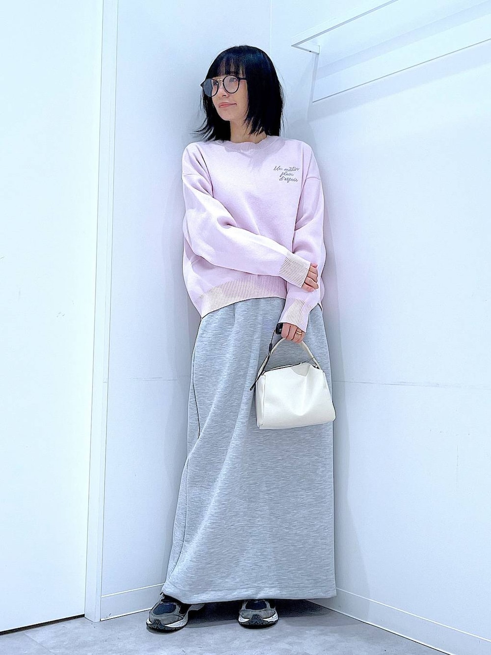 ホワイト系のショルダーバッグ、ピンク系のニット/セーター、グレー系のスカートを着用したレディースの冬コーディネートの1枚目の写真