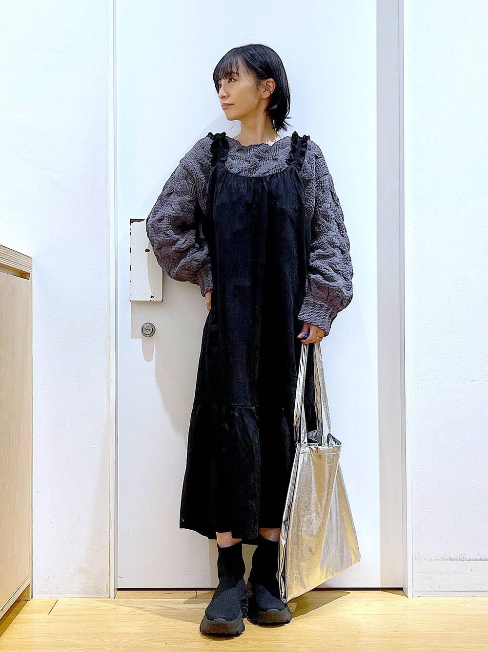 シルバー系のトートバッグ、ブラック系のブーツ、グレー系のニット/セーターを着用したレディースの冬コーディネートの1枚目の写真