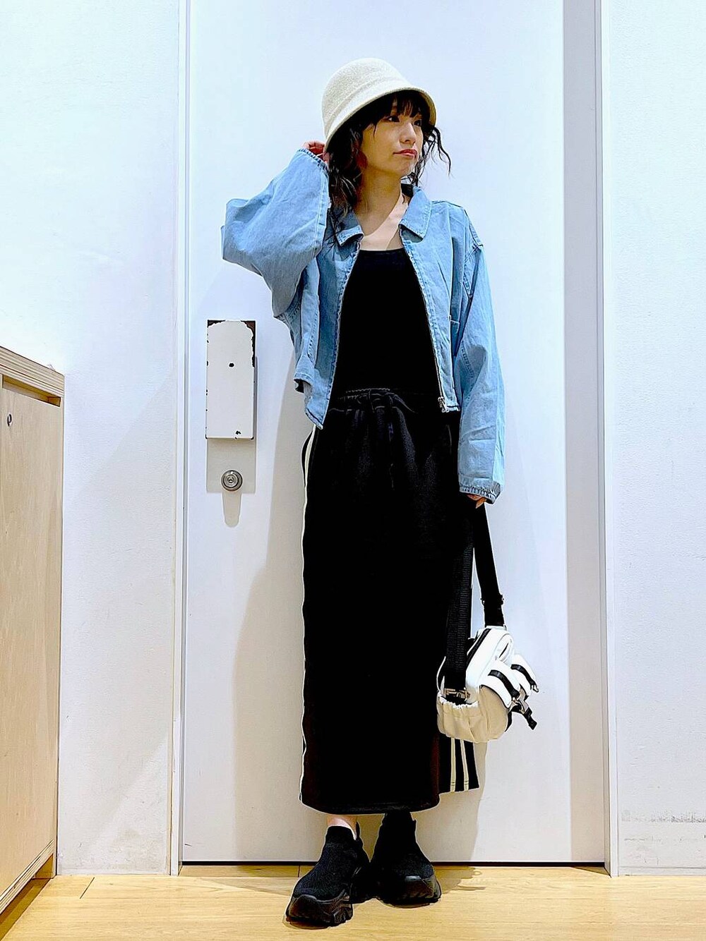 ブルー系のデニムジャケット、ブラック系のスカート、ブラック系のスニーカーを着用したレディースの春コーディネートの1枚目の写真