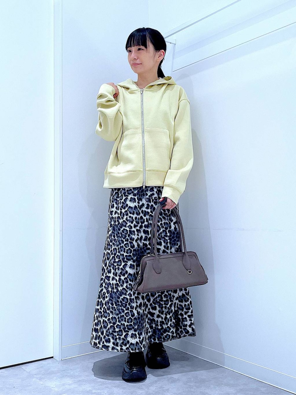 ブラック系のローファー、グレー系のスカート、イエロー系のパーカーを着用したレディースの秋コーディネートの1枚目の写真