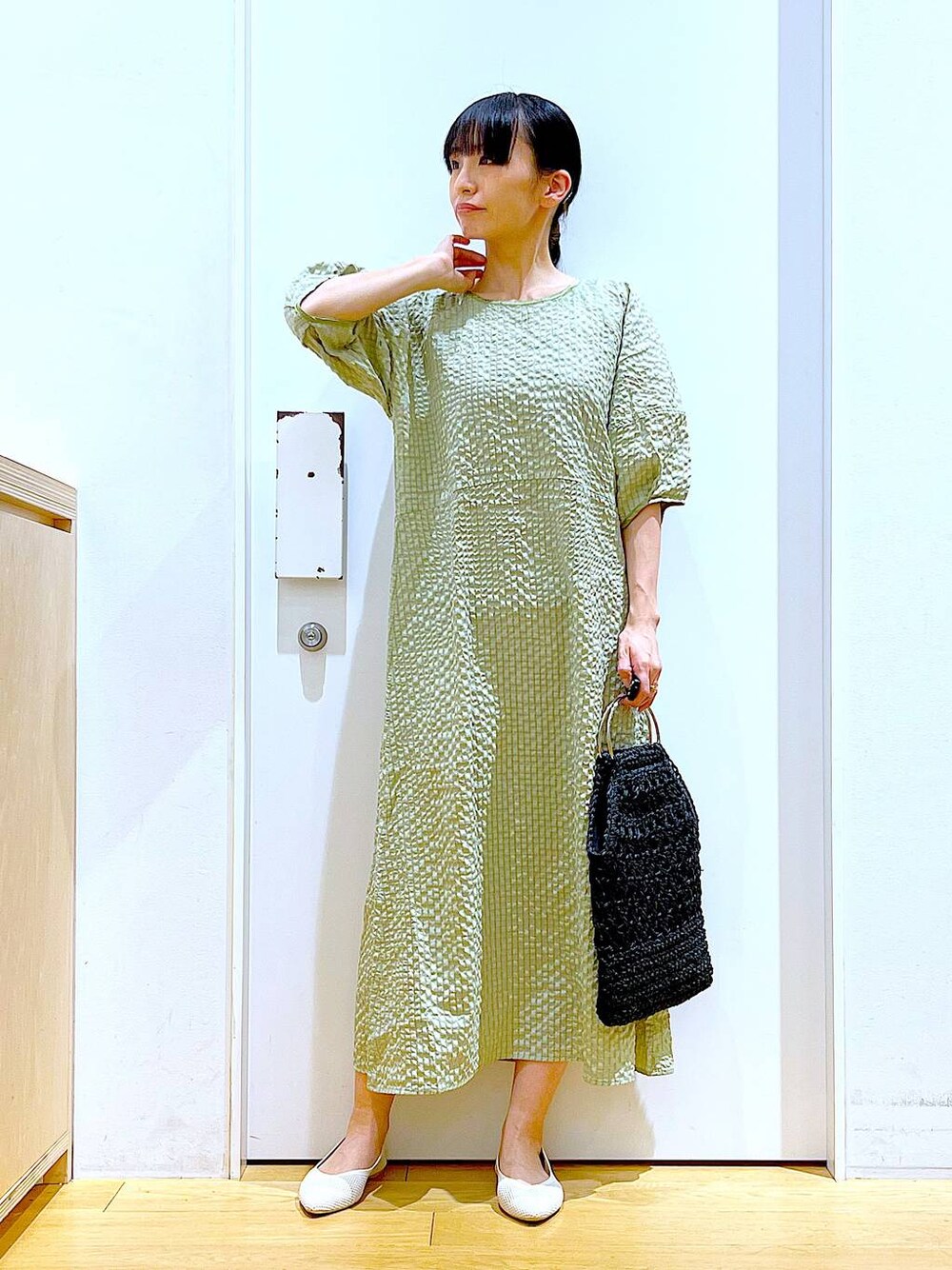 グリーン系のワンピース、ホワイト系のパンプス、ブラック系のハンドバッグを着用したレディースの春コーディネートの1枚目の写真