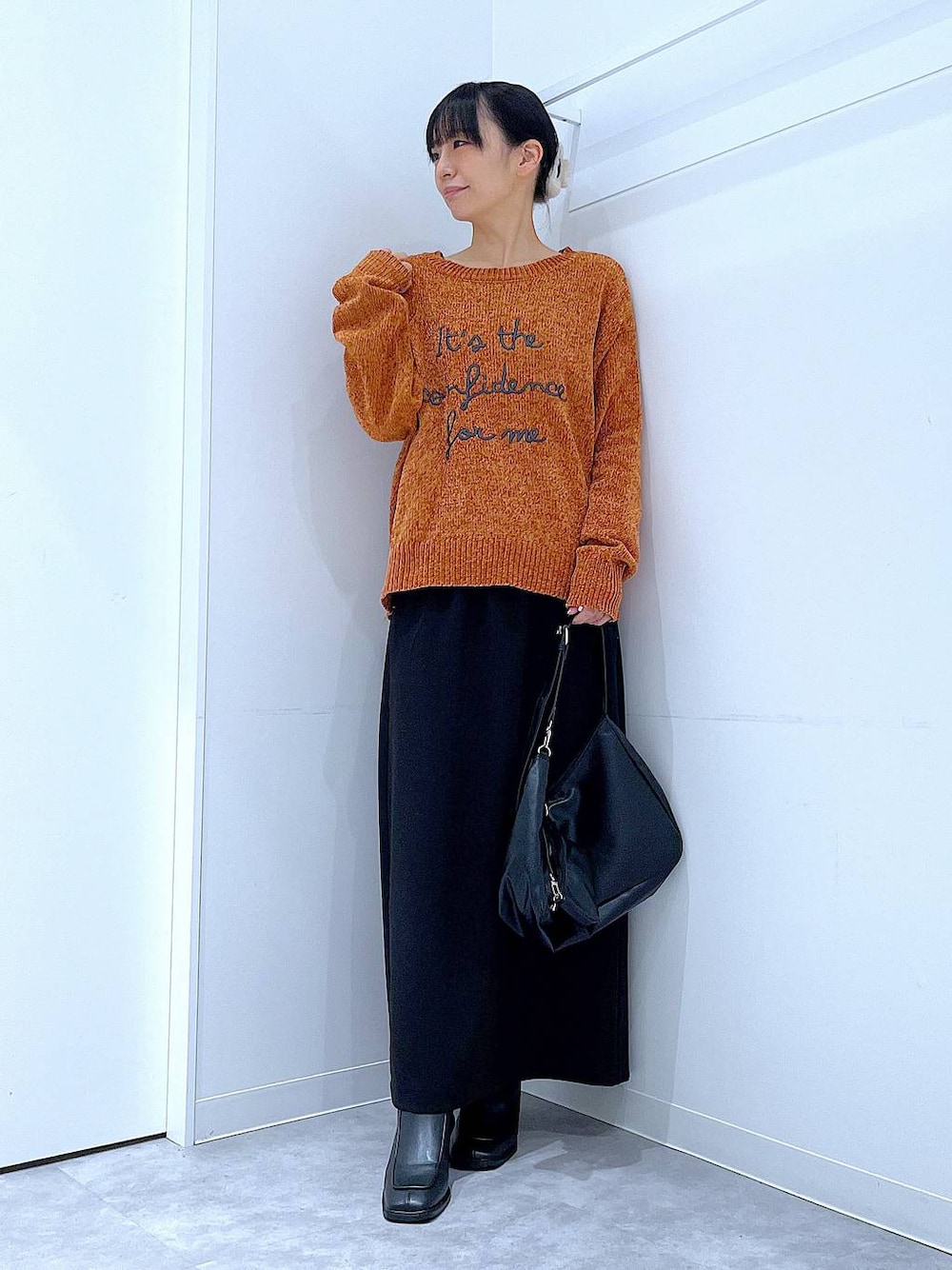 ブラック系のスカート、ブラック系のブーツ、ブラック系のショルダーバッグを着用したレディースの冬コーディネートの1枚目の写真